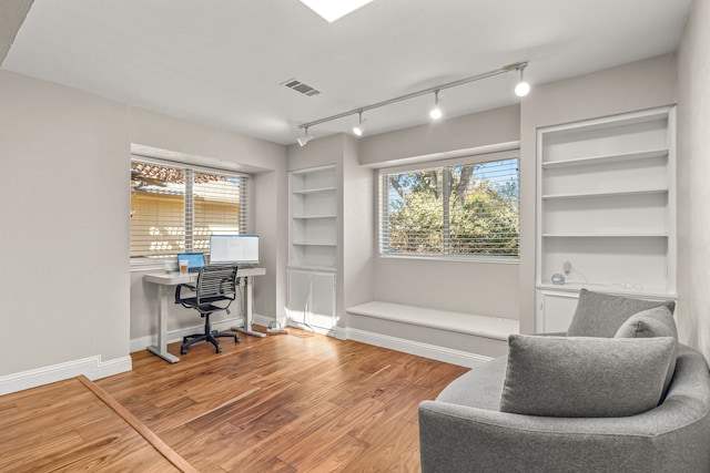 office space featuring visible vents, built in shelves, wood finished floors, and baseboards