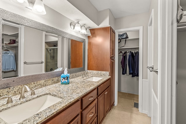 bathroom featuring a sink, a stall shower, double vanity, and tile patterned flooring