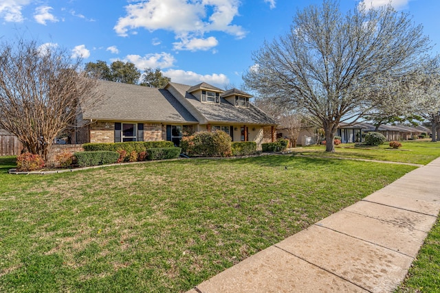 view of front of property with brick siding, a front yard, and roof with shingles