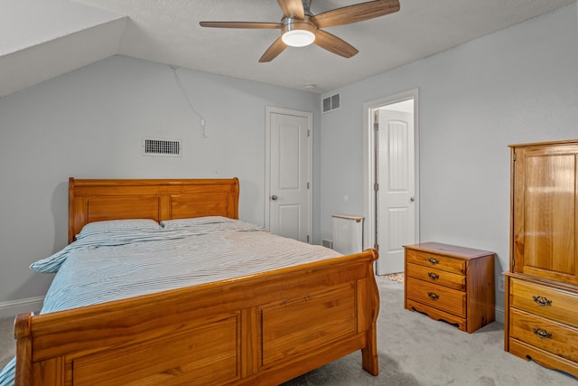 bedroom with a ceiling fan, vaulted ceiling, light colored carpet, and visible vents