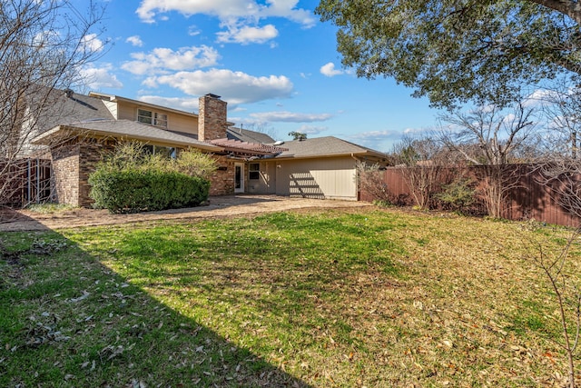 rear view of house featuring a lawn, a chimney, a patio, and fence