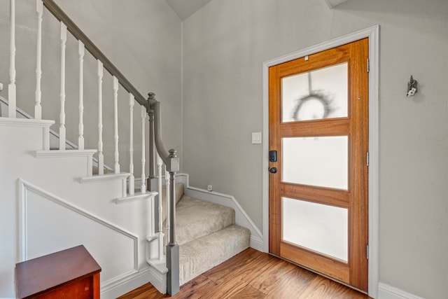 entryway with stairway, wood finished floors, and baseboards