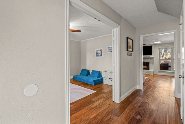 hall featuring baseboards, a textured ceiling, and wood finished floors