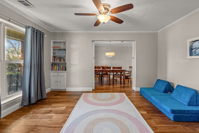 living room featuring visible vents, ornamental molding, a textured ceiling, and wood finished floors