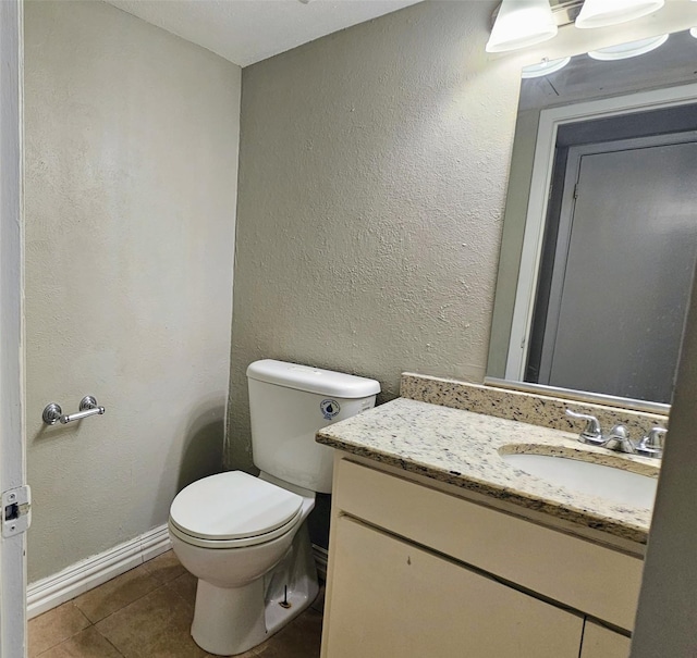 bathroom with baseboards, a textured wall, toilet, tile patterned floors, and vanity