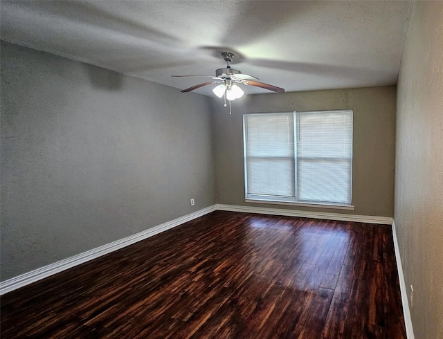 empty room featuring a textured ceiling, dark wood finished floors, a ceiling fan, and baseboards