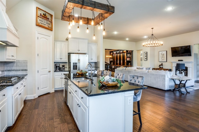 kitchen featuring stainless steel appliances, dark wood-type flooring, a kitchen bar, and a sink