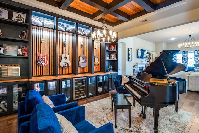 living area featuring beamed ceiling, coffered ceiling, a notable chandelier, and wood finished floors