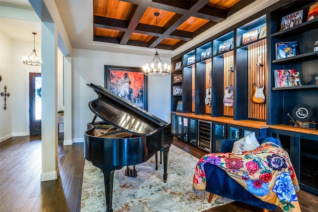 living area featuring baseboards, coffered ceiling, wood finished floors, a chandelier, and beam ceiling