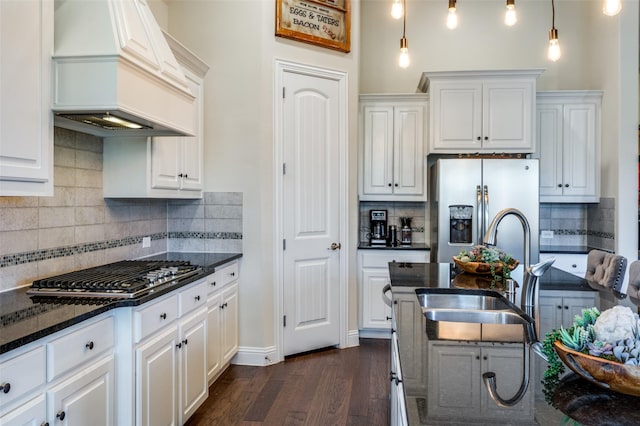 kitchen featuring custom range hood, a sink, appliances with stainless steel finishes, dark wood finished floors, and backsplash