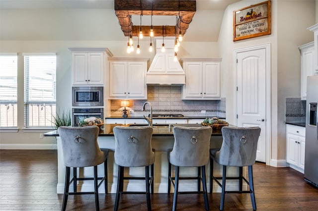 kitchen with a breakfast bar, custom exhaust hood, dark countertops, backsplash, and appliances with stainless steel finishes