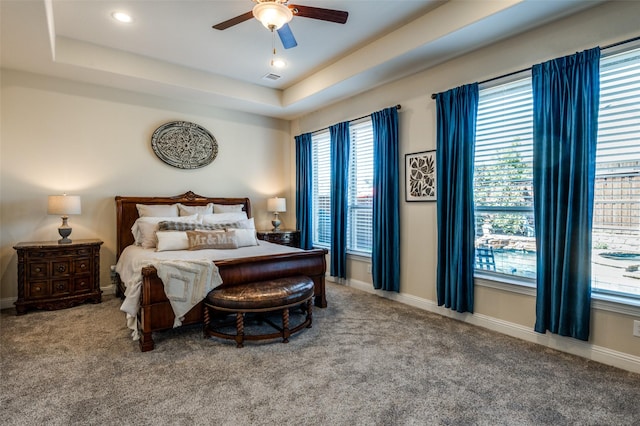 bedroom featuring a raised ceiling, carpet flooring, and baseboards