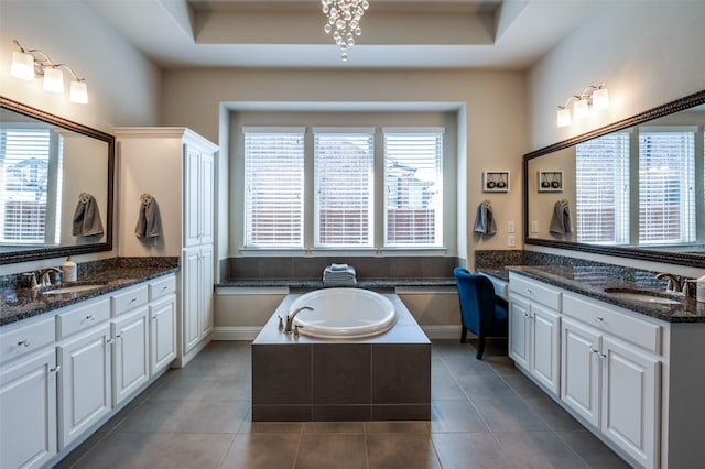 bathroom featuring a garden tub, two vanities, and a sink