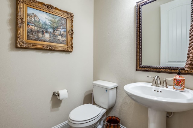 bathroom with baseboards, a sink, and toilet