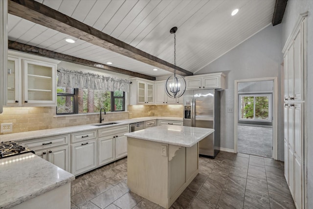 kitchen with appliances with stainless steel finishes, a kitchen island, plenty of natural light, and a sink