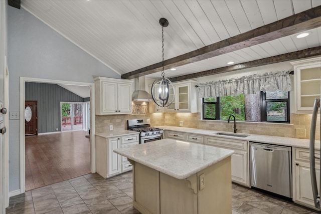 kitchen featuring a center island, vaulted ceiling with beams, stainless steel appliances, wall chimney range hood, and a sink