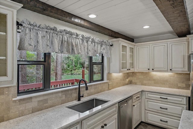 kitchen with a sink, beam ceiling, light stone counters, and dishwasher