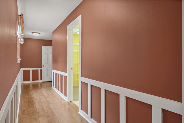 corridor with light wood-style flooring and an upstairs landing