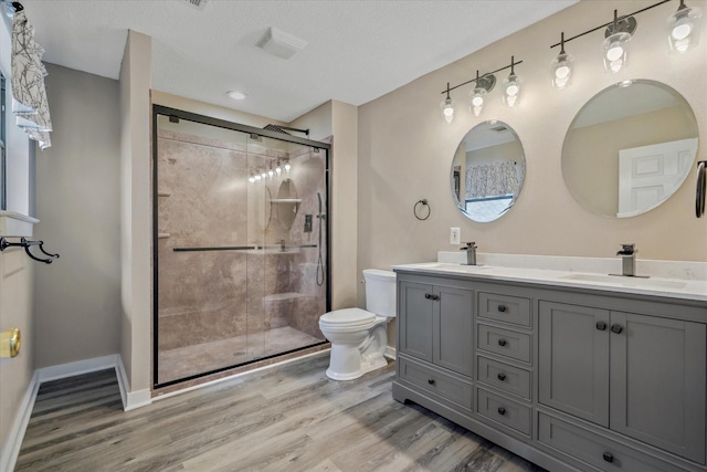 bathroom featuring wood finished floors, a sink, toilet, and a shower stall