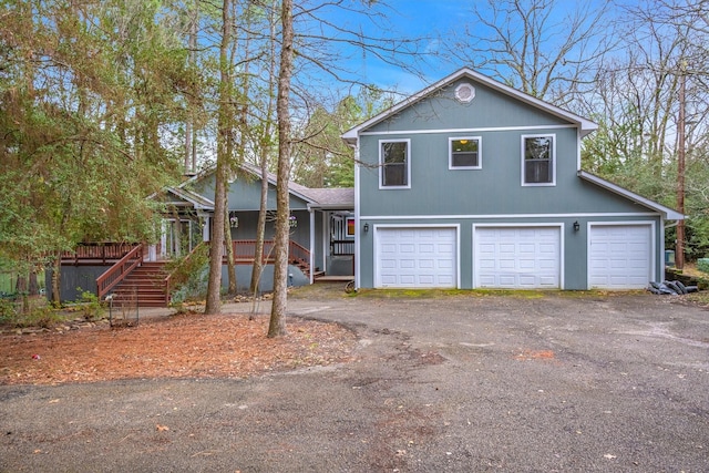 view of front facade with covered porch, driveway, an attached garage, and stairs