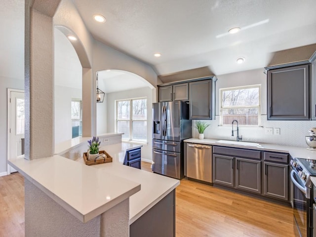 kitchen with light wood-style flooring, appliances with stainless steel finishes, light countertops, and a sink