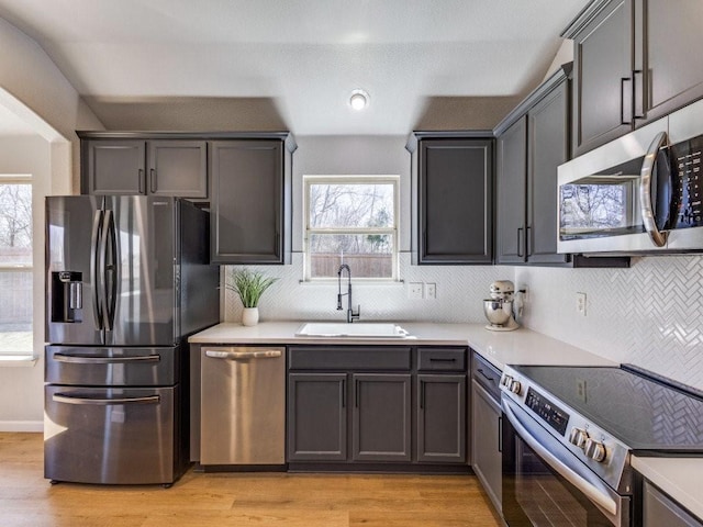 kitchen featuring appliances with stainless steel finishes, light countertops, a healthy amount of sunlight, and a sink