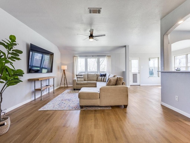 living room with visible vents, a textured ceiling, baseboards, and wood finished floors