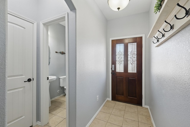 doorway with baseboards and light tile patterned floors