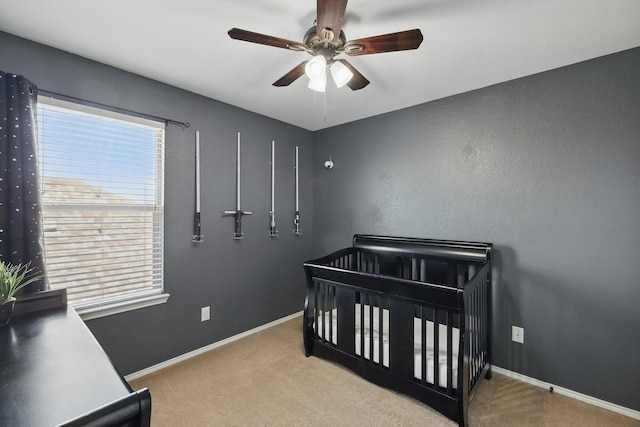 carpeted bedroom with a nursery area, ceiling fan, and baseboards