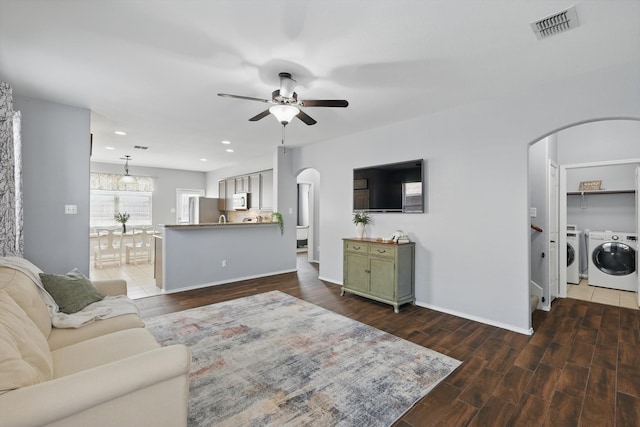 living room featuring visible vents, arched walkways, a ceiling fan, wood finished floors, and independent washer and dryer