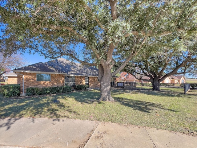 ranch-style house with brick siding, fence, and a front yard