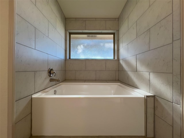 bathroom featuring a bath and tile walls