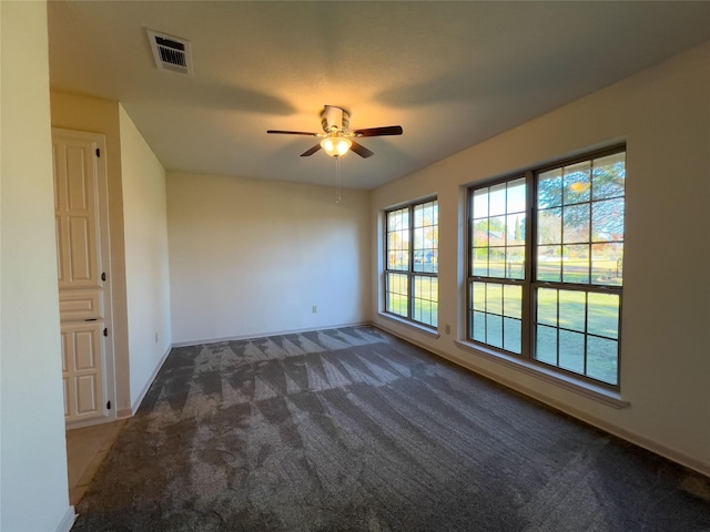 spare room featuring carpet, visible vents, ceiling fan, and baseboards