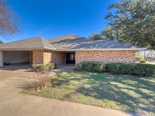 ranch-style home with driveway, a shingled roof, an attached garage, a front lawn, and brick siding