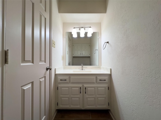 bathroom featuring tile patterned flooring, a textured wall, and vanity