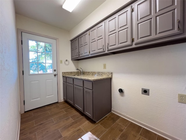 laundry area with a sink, cabinet space, electric dryer hookup, and wood finish floors