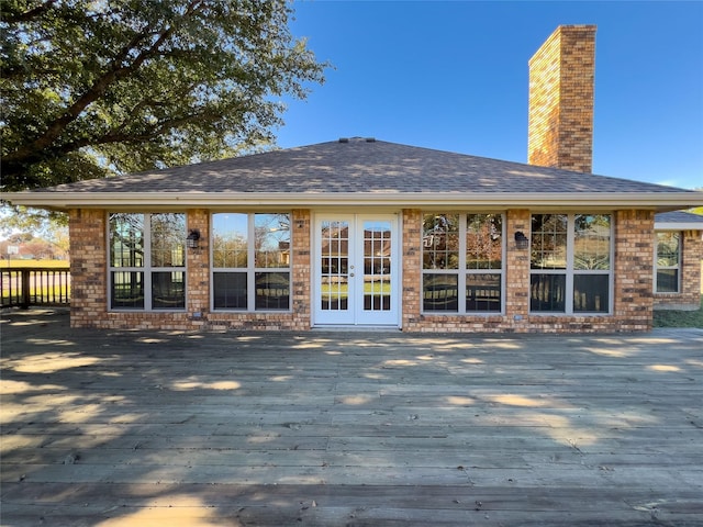 rear view of property featuring a shingled roof, a chimney, a deck, and french doors