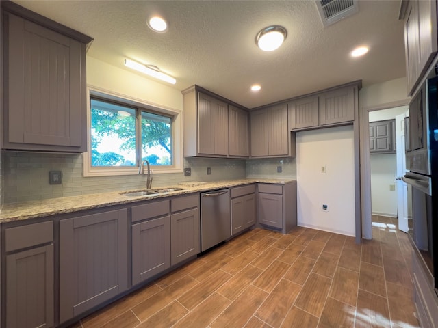 kitchen with visible vents, dishwasher, light stone countertops, gray cabinetry, and a sink