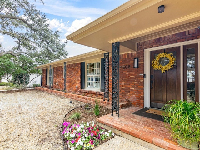 entrance to property with covered porch and brick siding