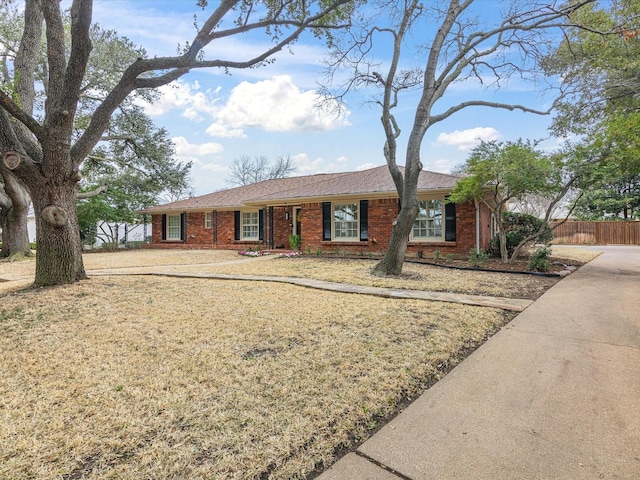 ranch-style home featuring brick siding and fence