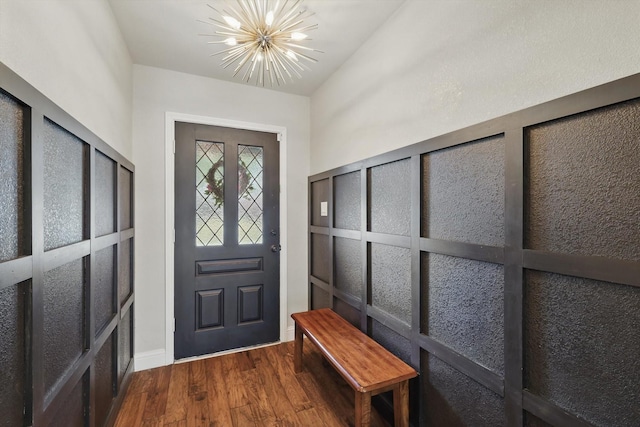 foyer with a chandelier, dark wood-type flooring, and baseboards