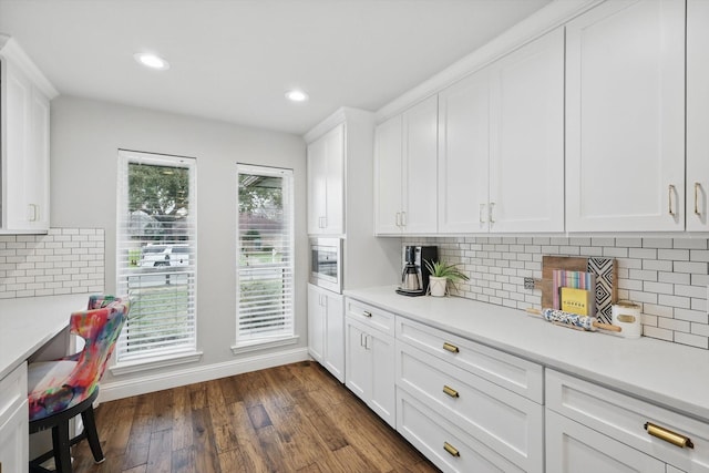 kitchen with white cabinets, decorative backsplash, dark wood finished floors, light countertops, and recessed lighting