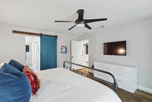 bedroom featuring ceiling fan, a barn door, dark wood-style flooring, visible vents, and baseboards