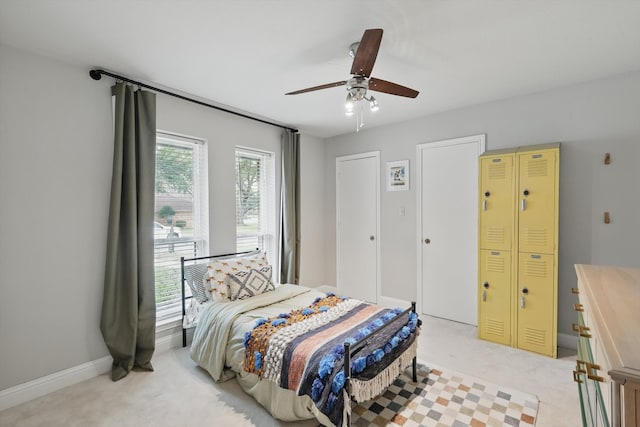 bedroom with a ceiling fan, light colored carpet, and baseboards