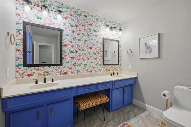 bathroom featuring baseboards, a sink, toilet, and double vanity