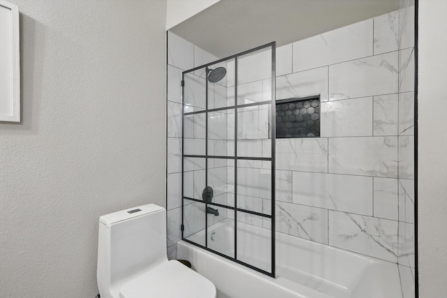 bathroom with enclosed tub / shower combo, a textured wall, and toilet