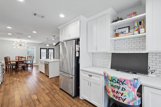 kitchen with hardwood / wood-style flooring, visible vents, white cabinetry, light countertops, and appliances with stainless steel finishes