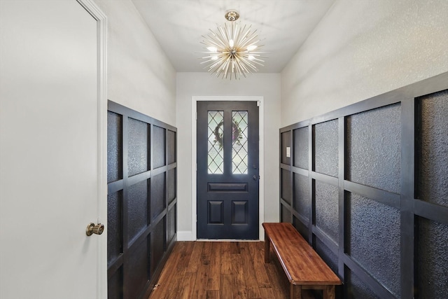 foyer featuring a notable chandelier, baseboards, and dark wood-type flooring