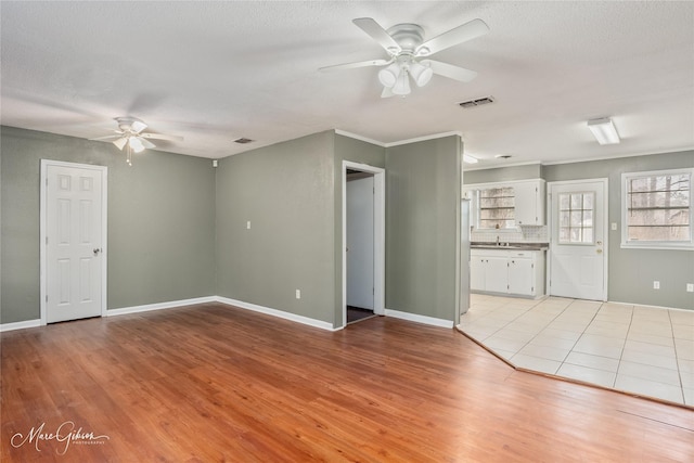 unfurnished living room with light wood-type flooring, visible vents, and ceiling fan