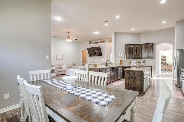 dining room featuring light wood finished floors, arched walkways, a ceiling fan, and recessed lighting